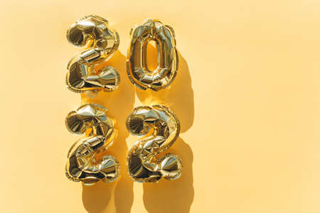 Balloons made of gold foil with the numbers 2022 on a gold background. Celebrating Christmas, New Years and holiday concept.の写真素材