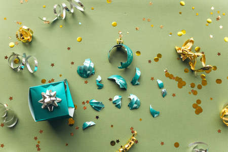 A broken Christmas tree toy ball on a green background in a minimalist style. The concept of the end...