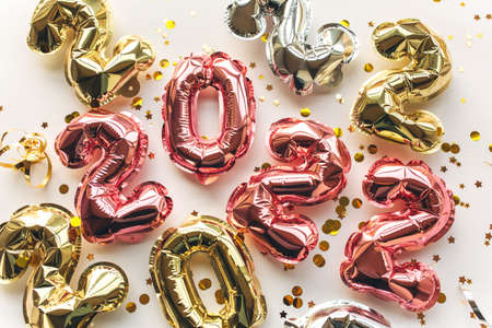 Multicolored Balloons made of foil in the form of numbers 2022 with confetti on a pink background . Celebrating Christmas, New Year and festive concept. Flat lay, top view.の写真素材