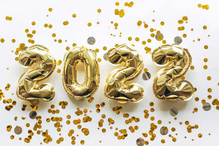 Balloons made of gold foil with the numbers 2022 on a white background with gold sequins. Celebrating Christmas, New Years and holiday concept. Flat lay, top view.の写真素材