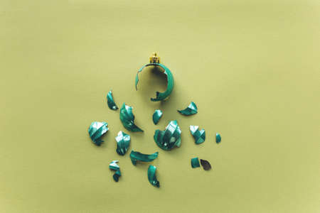 Broken Christmas tree toy ball on a green background in a minimal style. The concept of an unsuccessful new year celebration. Flat lay, top viewの写真素材