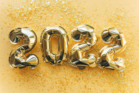 Balloons made of gold foil with the numbers 2022 on a gold background. Celebrating Christmas, New Years and holiday concept.の写真素材