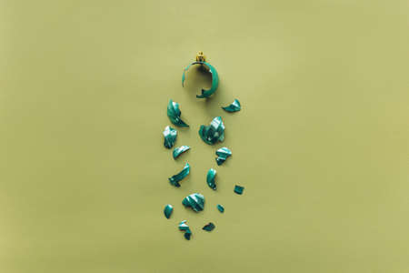 Broken Christmas tree toy ball on a green background in a minimal style. The concept of an unsuccessful new year celebration. Flat lay, top viewの写真素材