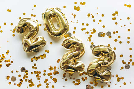 Balloons made of gold foil with the numbers 2022 on a white background with gold sequins. Celebrating Christmas, New Years and holiday concept. Flat lay, top view.の写真素材