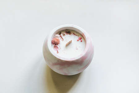 Ecological and vegan handmade candle on a white background with dry flowers in a glass made of concrete. Soy or coconut candle with a wooden wick..の写真素材