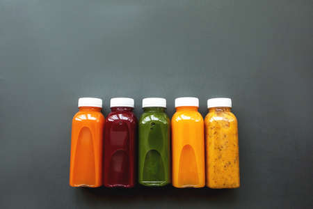 Fresh juices or cocktails of fruits and vegetables in bottles on a gray background. The concept of a healthy diet or dietの写真素材