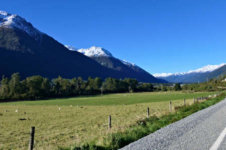 Mountain road in the Southern Alps in New Zealand on a winter day with a clear blue sky and snowy peaksの写真素材