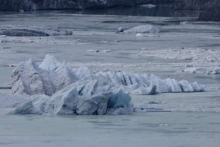 Blocks of ice from iceberg are drifting and melting on a half frozen lakeの写真素材