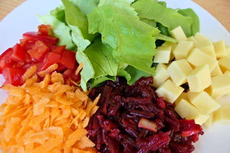 Closeup healthy homemade vegetarian high-protein salad plate with a mix of green lettuce, grated carrots and beetroot and chopped tomatoes and cheeseの写真素材