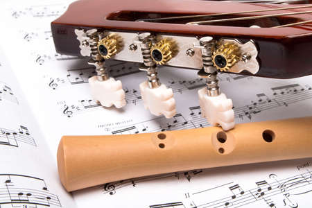 Guitar and wooden flute on sheet music. Close up.の写真素材