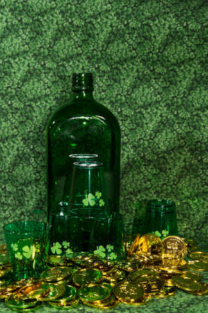  Bottle and shamrock shot glasses surrounded by gold coins on green background, Vertical の写真素材