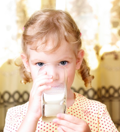 small beautiful girl drinks milk from a glassの写真素材