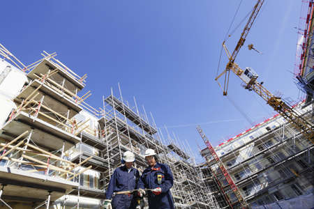 building workers surrounded by cranes and scaffoldingの写真素材