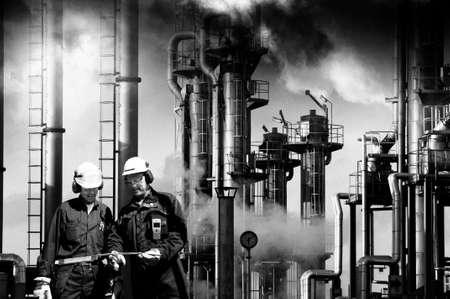 two refinery workers with industrial plant in backgroundの写真素材