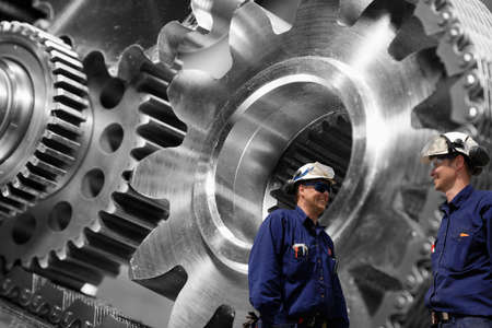 steel mechanics, workers with giant cogwheels and pinions machineryの写真素材