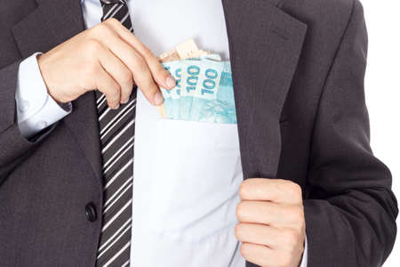 A businessman in a suit putting money in his pocket isolated on white background