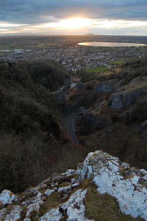 View of Cheddar,UK from the cliffs. We can see the narrow twisted road down below and the whole town at sunset.の写真素材