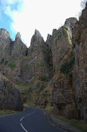 Looking up at Cheddar cliffs from the narrow twisted road. The sky is bright blue and cloudedの写真素材