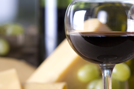 Wine bottle with a glass of red wine with cheese and grapesの写真素材