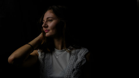 Portrait of a beautiful young woman on a black background in the darkの写真素材