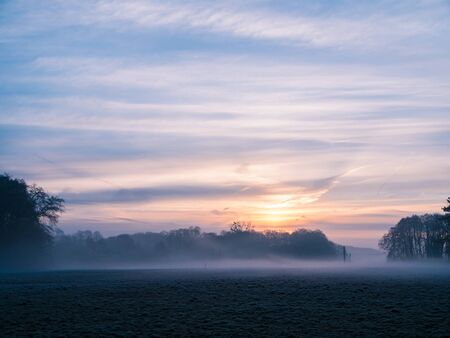 Beautiful sunrise over a misty field in Germanyの写真素材