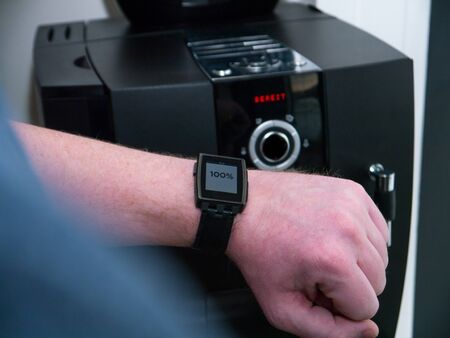Smart Home: Man checking the status of a coffee machine with his smart watch