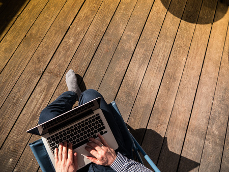 Home Office: Young man working with his laptop on a terraceの写真素材
