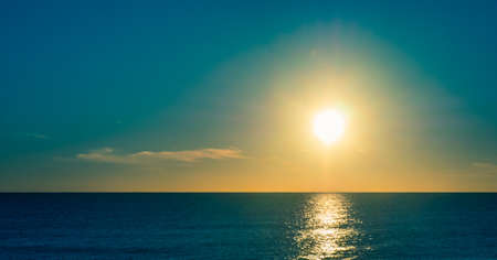 Sunset at the beach with sun in the sky.の写真素材