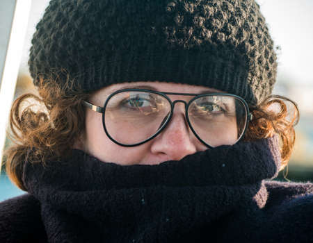 Close of woman with cap and glasses looking at camera.の写真素材