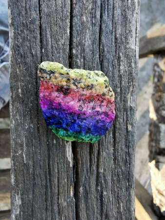 LGBT colors Painted Rock over wooden background.