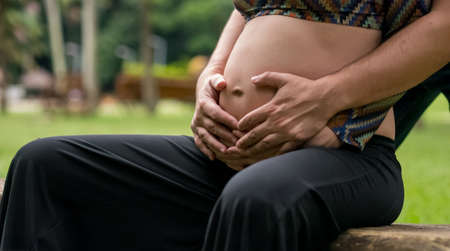 Close of pregnant wife and husband touching belly.