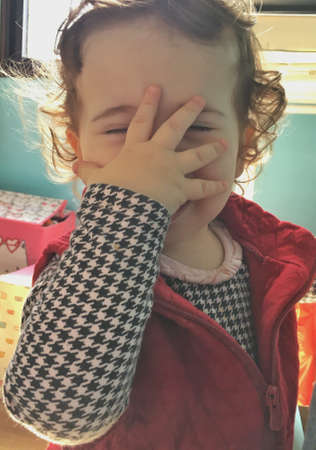 Funny Little baby girl with hand on face.