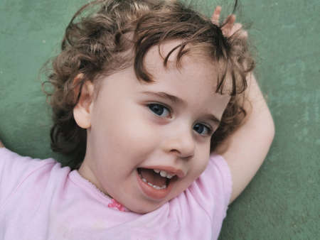 View of little girl playing on the a green floor.の写真素材