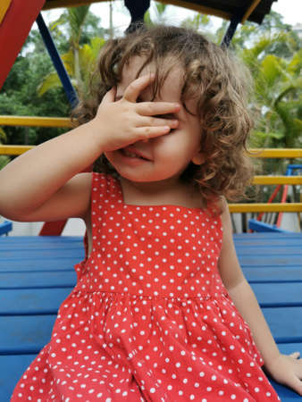 little girl playing covering her face with her handの写真素材