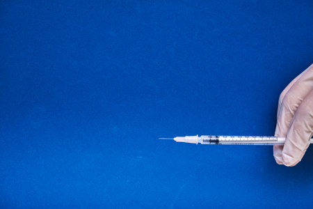 View of a medical hand ready to give injection on blue background with copy space.の写真素材