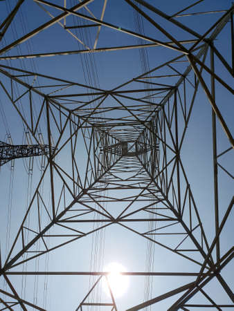 Under view of power tower over blue sky.