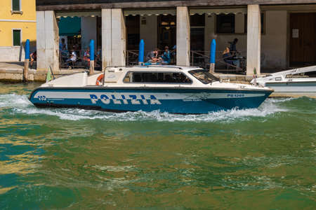 VENICE, ITALY - August 27, 2021: Police boat sailing on a typical Venetian water street canals.の写真素材