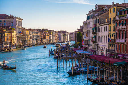 View of facades of picturesque old buildings on the Grand Canal, gondolas and boats in Venice. Sunny...