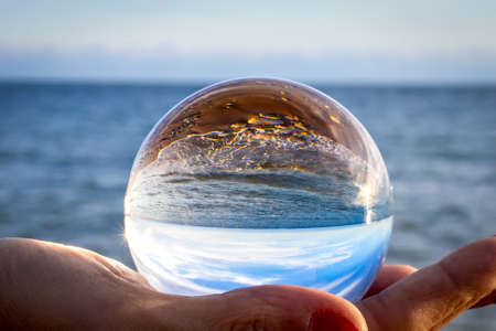 sea seen through a glass ball held in one handの写真素材