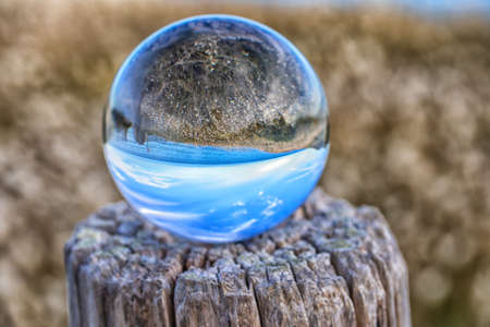 beach seen in a glass ball placed on a trunkの写真素材