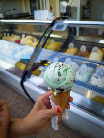 hand holding an ice cream in front of an ice cream shop
