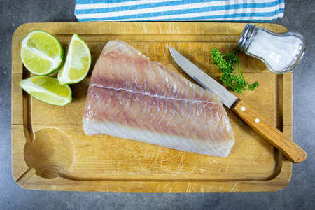 raw fish fillet (saithe) on a cutting board