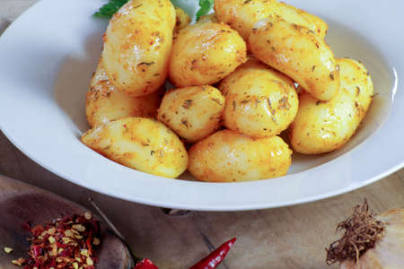 boiled potatoes with fresh herbs and spices on a white plateの写真素材