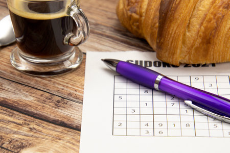 sudoku sheet on a table with a coffee and croissantの写真素材