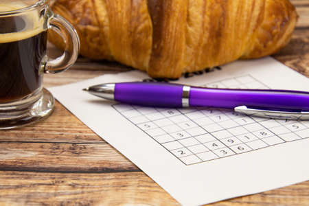 sudoku sheet on a table with a coffee and croissantの写真素材
