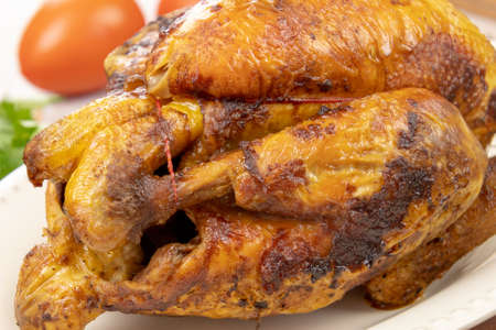 close up view of delicious whole grilled chicken on wooden board