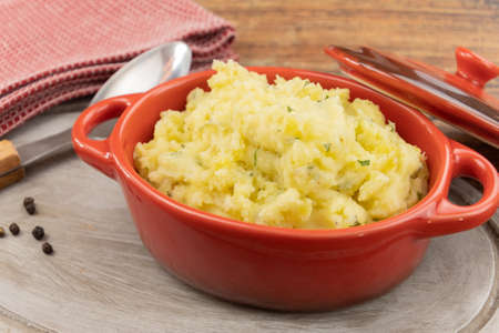 red casserole with creamy mashed potatoes on wooden tableの写真素材