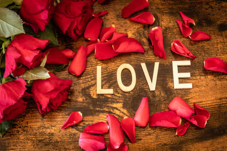 Background with lit candles and rose petals and the word loveの写真素材