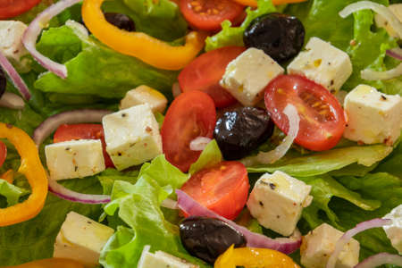 green salad with vegetables and feta in a plate on a tableの写真素材