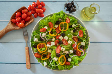 green salad with vegetables and feta in a plate on a tableの写真素材